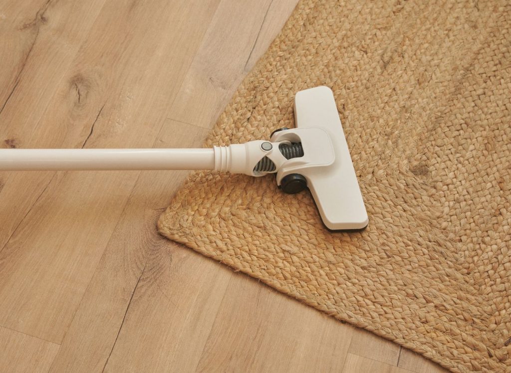 A vacuum cleaner resting on a wooden floor, highlighting a rug cleaning service based in Jacksonville, FL.